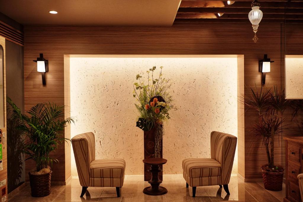 a lobby with two chairs and a vase of flowers at Ryuka Hotel Naha in Naha