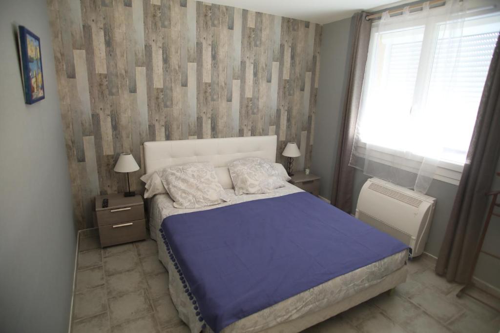 um quarto com uma cama com um edredão azul e uma janela em B&B La Campagne em Roquevaire