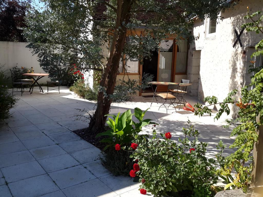 un patio con tavolo, sedie e fiori di La Clé des Chants a Tauxigny
