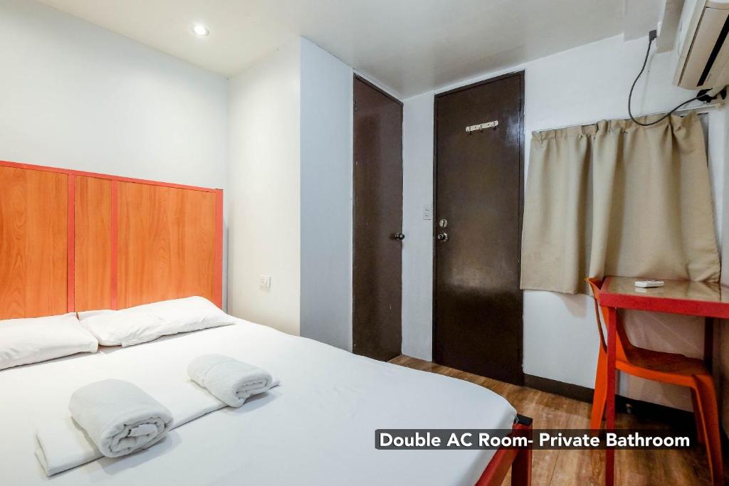 a bedroom with a white bed with a wooden headboard at Stay Malate (Wanderers Guest House) in Manila