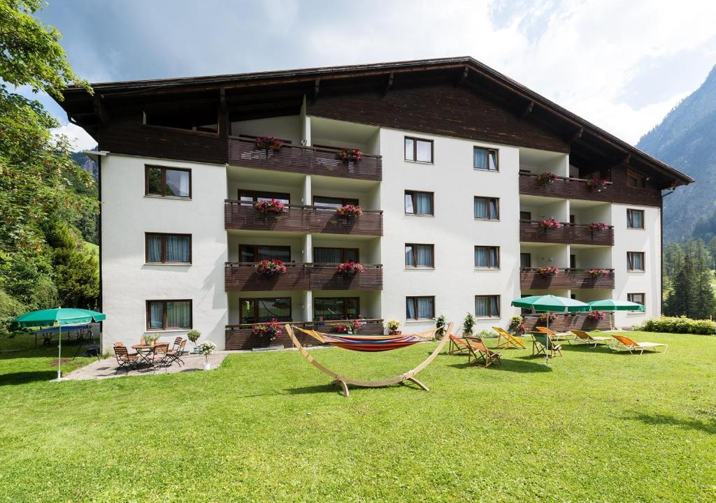 un hôtel avec des chaises et des tables dans la pelouse dans l'établissement Appartementhaus Egga, à Brand
