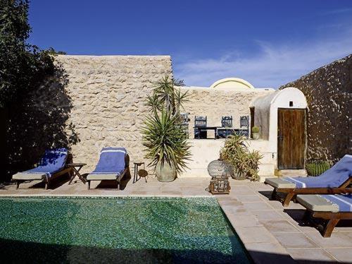 a patio with chairs and a pool in front of a building at Hotel Dar Dhiafa in Houmt Souk