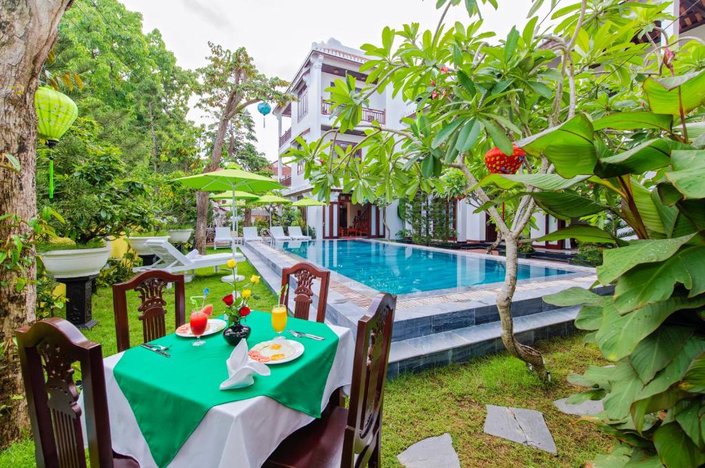 una mesa con un paño verde junto a una piscina en Green Hill Villa, en Hoi An