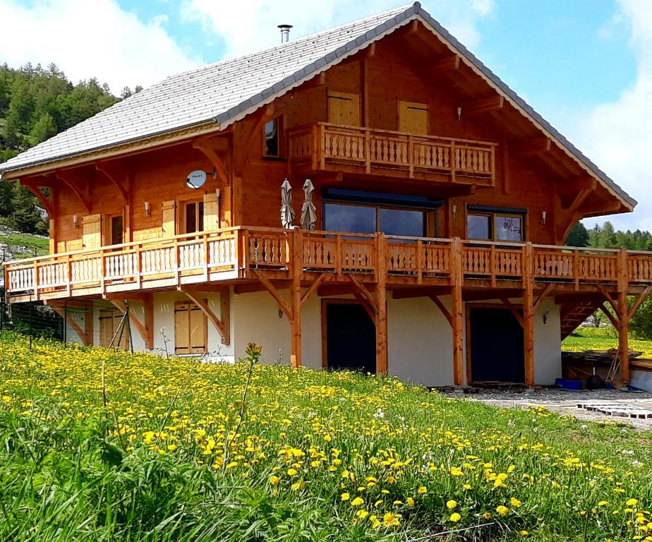 une grande maison en bois avec une terrasse sur une colline dans l'établissement Chalet TERRA LOUP, à Saint-Étienne-en-Dévoluy