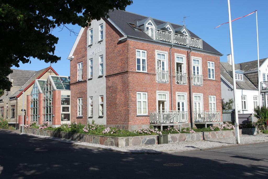 ein großes rotes Backsteingebäude mit weißen Fenstern und Balkonen in der Unterkunft Hotel Nysted Havn in Nysted
