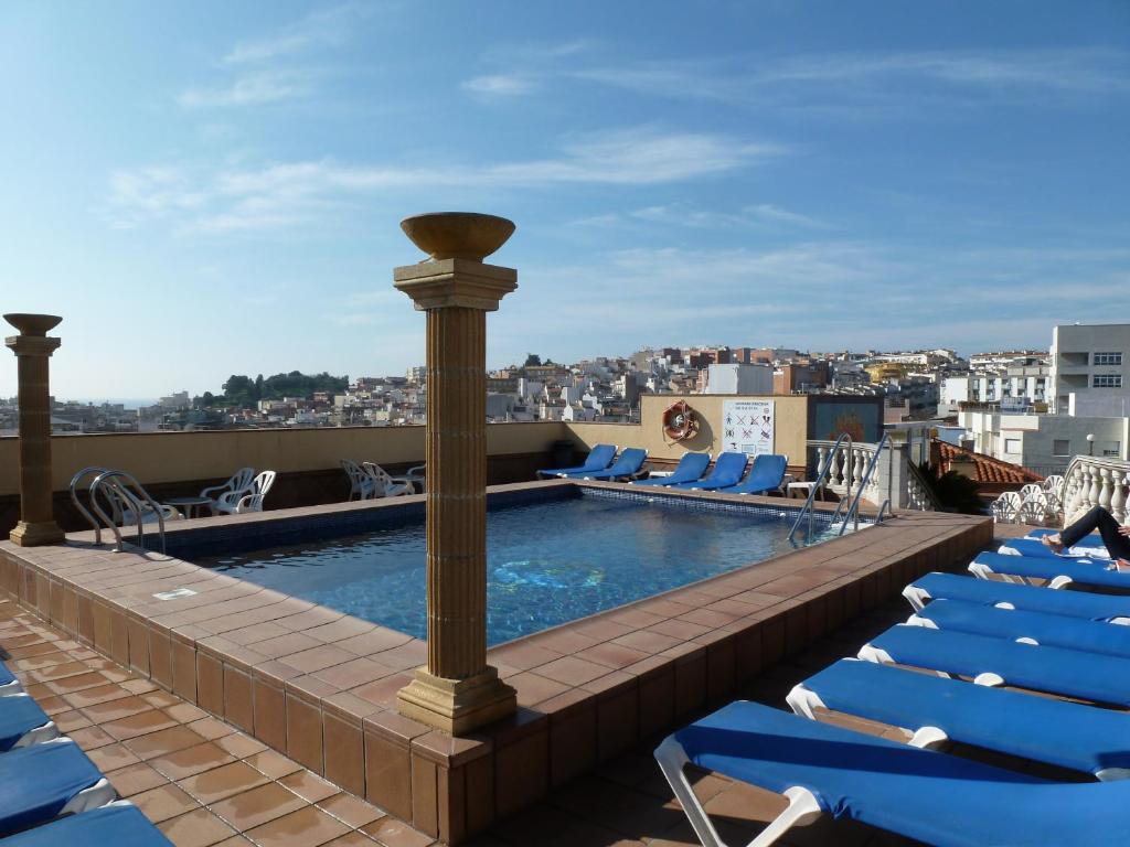 a pool on the roof of a building with lounge chairs at Hotel Costa Brava in Blanes