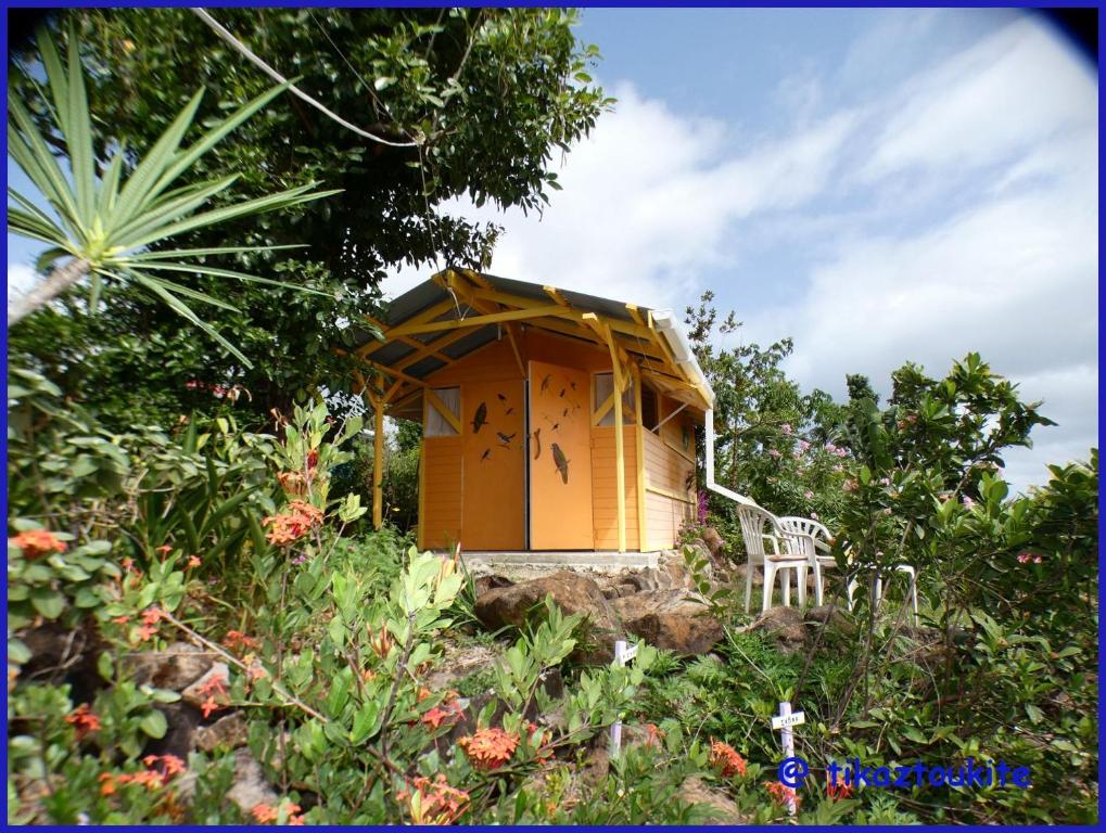 ein kleines gelbes Haus mit einem Stuhl im Garten in der Unterkunft Tikaz Toukité in Méro