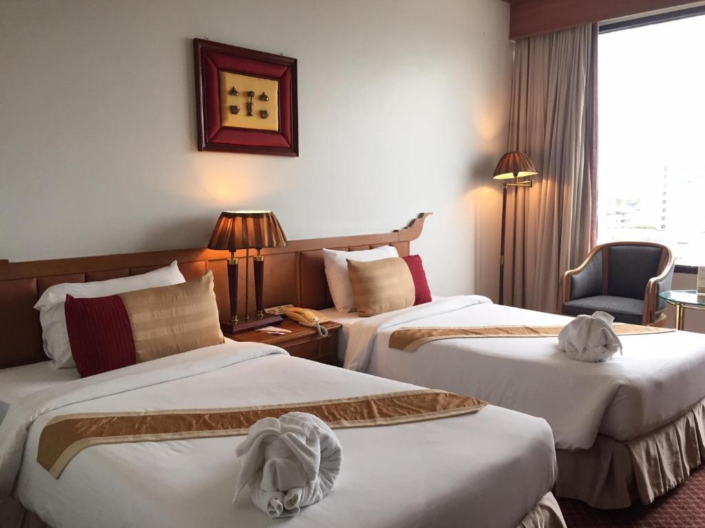 a hotel room with two beds and a chair at Laithong Hotel in Ubon Ratchathani
