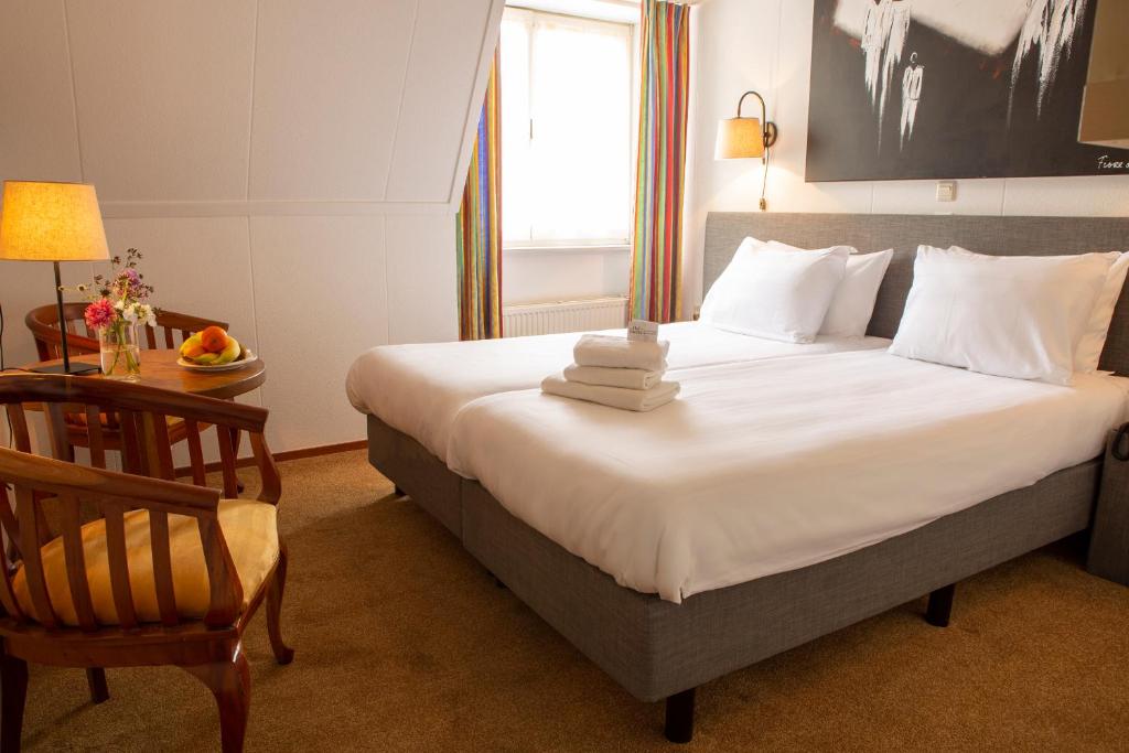 a bedroom with a bed with a chair and a window at Hotel Hof van Twente in Hengevelde