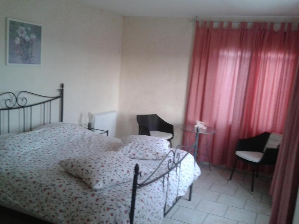 1 dormitorio con 1 cama, 2 sillas y cortinas rojas en Chambres d'hôtes La Prairie en Belley