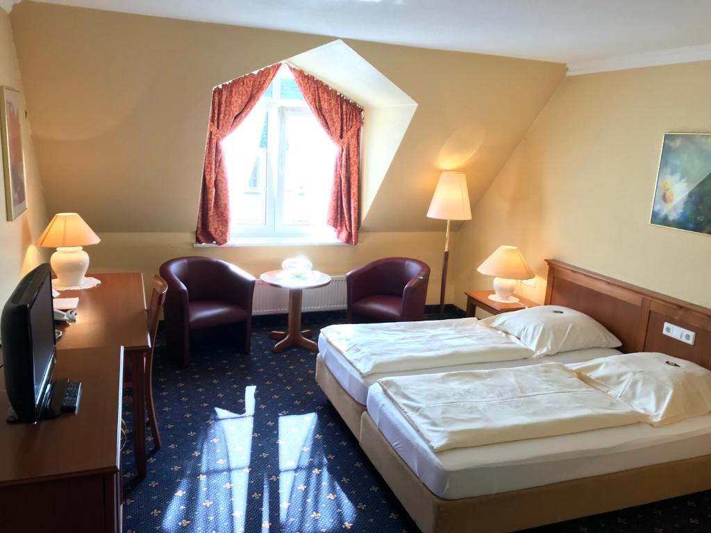a hotel room with two beds and a table and a window at Holskenbänd in Horstmar