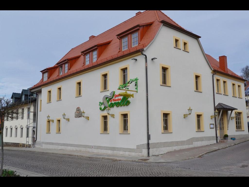 Pension Gasthaus Zur Forelle في Seeburg: مبنى ابيض كبير بسقف احمر
