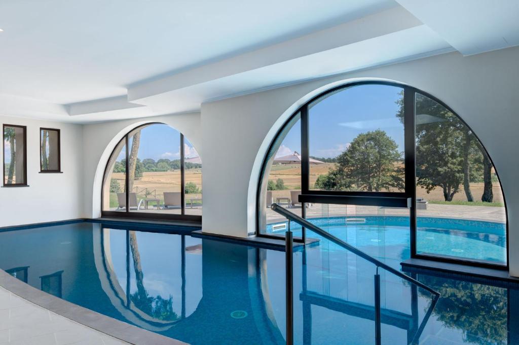 an indoor swimming pool with three windows and a large swimming pool at Borgo La Chiaracia Resort & SPA in Castel Giorgio