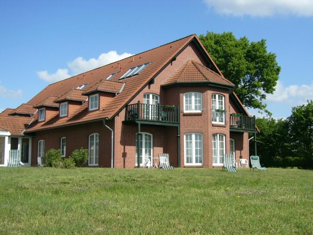 a large brick house with chairs in the grass at Hotel Marianne und Restaurant Kiek In in Plau am See