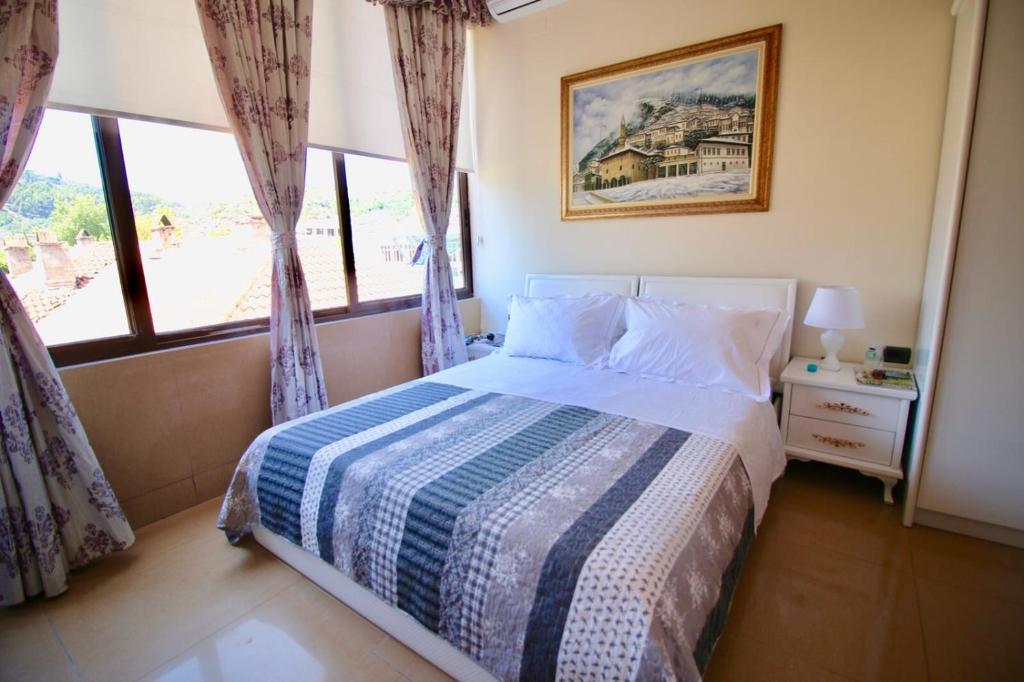 a bedroom with a bed with a blue and white blanket at Hotel Orestiada in Berat