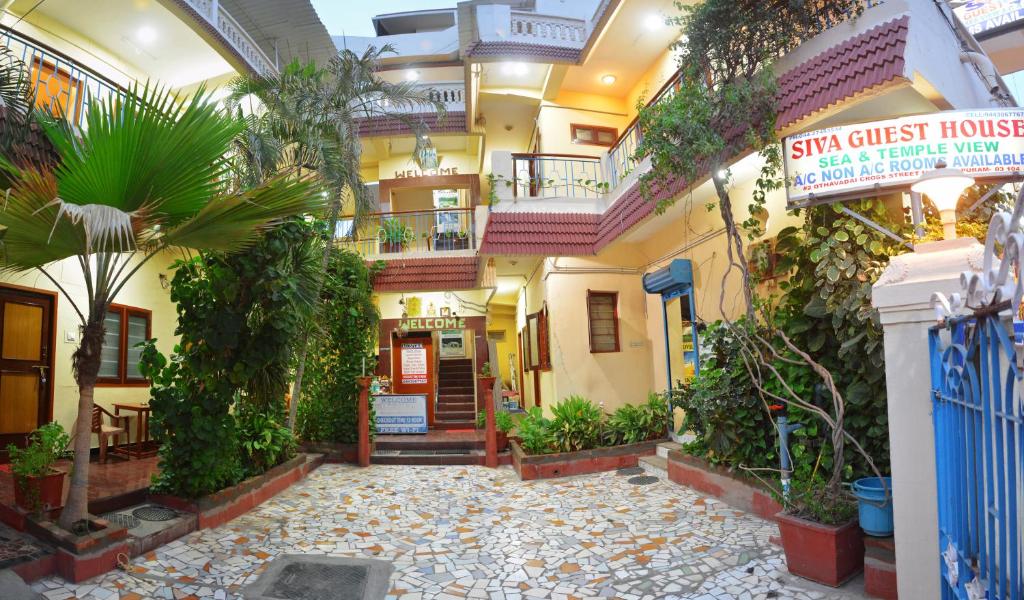 a building with a courtyard with many plants and trees at Siva Guest House in Mahabalipuram