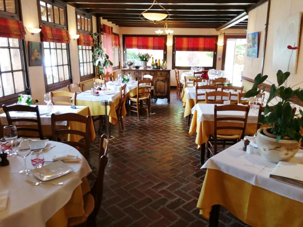 a restaurant with tables and chairs with white tablecloths at Auberge du Vieux Tour in Canapville