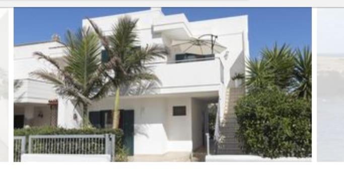 una casa blanca con una palmera delante de ella en Villa Irene, en Torre Santa Sabina