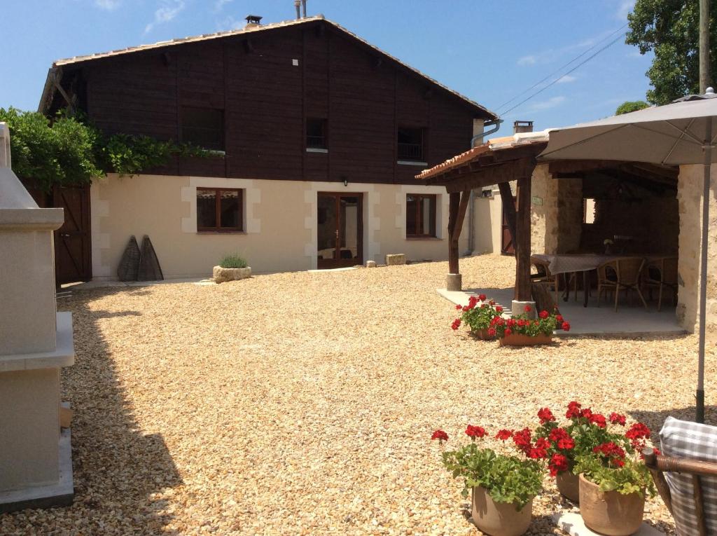 une maison avec une cour fleurie devant elle dans l'établissement La Maison du Lac****, à Saint-Martin-de-Gurçon