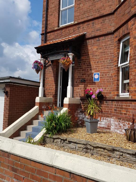 a brick building with stairs and flowers in front of it at Autumn Leaves Guest House in Whitby