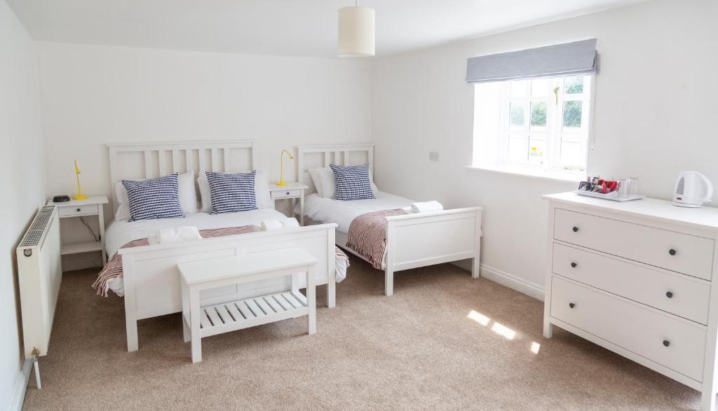 a white bedroom with two beds and a window at Five Bells Inn, Wrentham in Wrentham