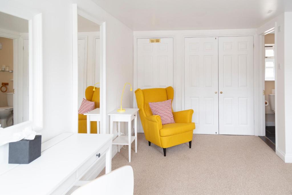 a living room with a yellow chair and a table at Five Bells Inn, Wrentham in Wrentham