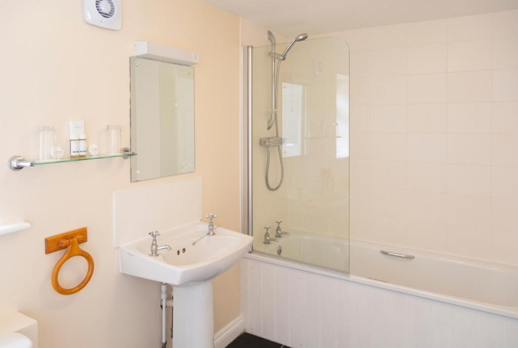 a white bathroom with a sink and a shower at Five Bells Inn, Wrentham in Wrentham
