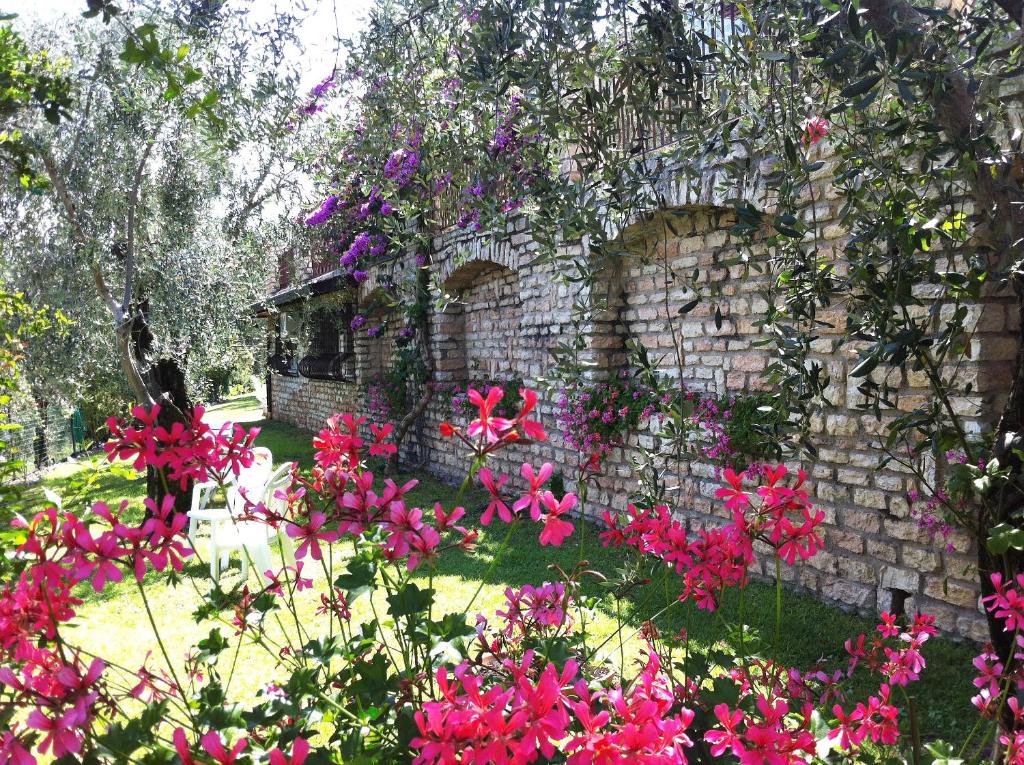 a garden with pink flowers in front of a stone building at Hotel Villa Margherita in Limone sul Garda