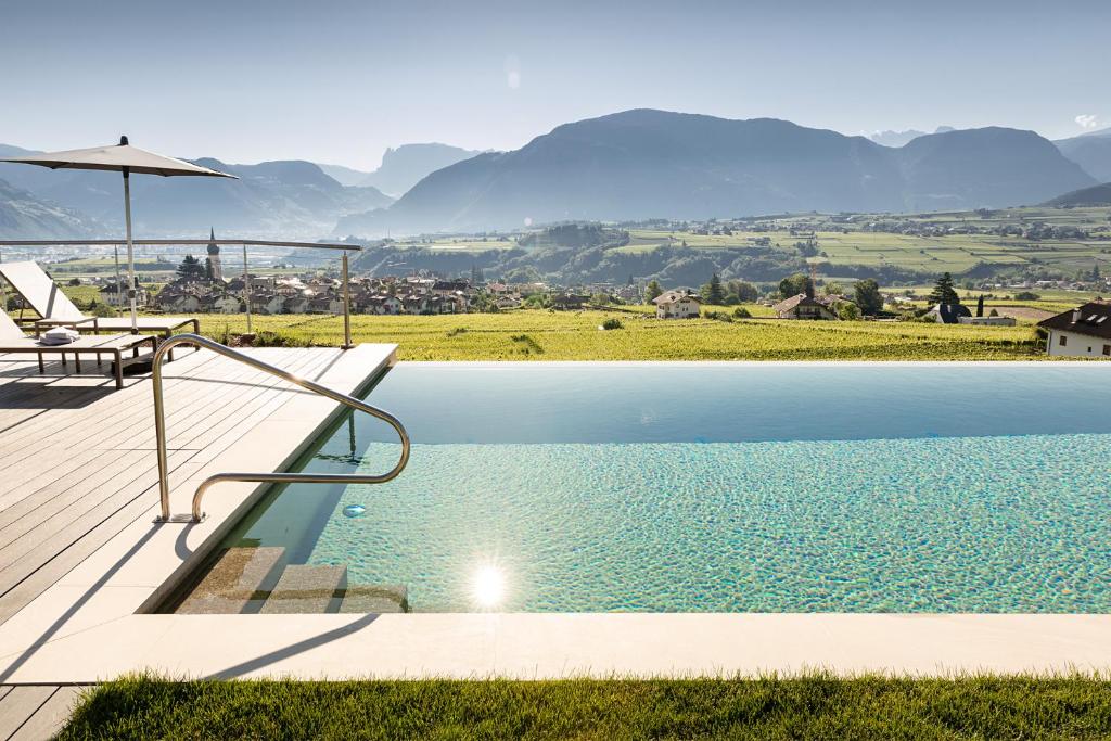 a swimming pool with a table and an umbrella at Mederle Hof in Appiano sulla Strada del Vino