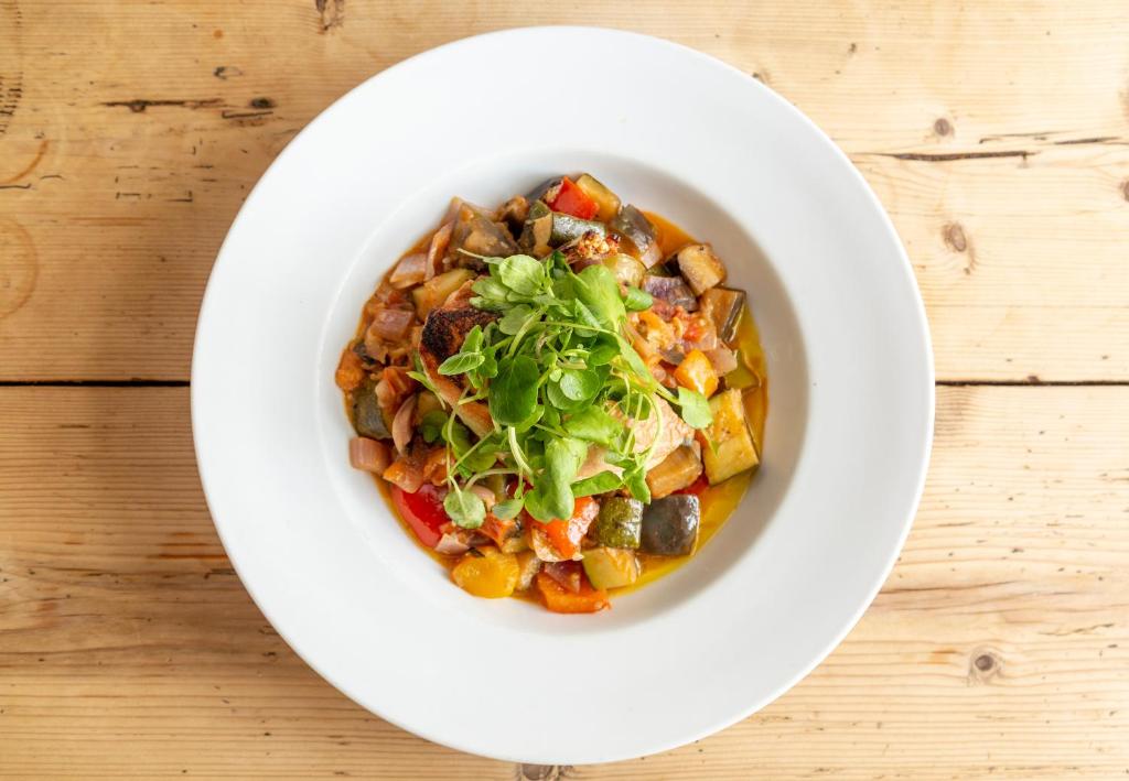 a white bowl filled with food on a wooden table at Five Bells Inn, Wrentham in Wrentham