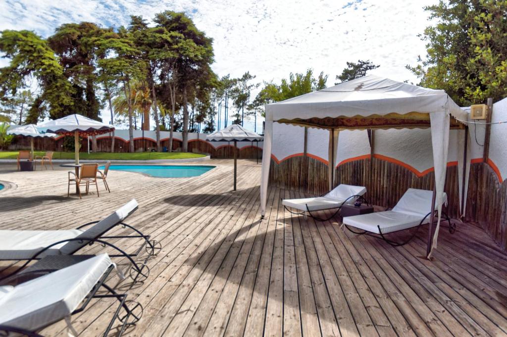 a deck with chairs and a tent next to a pool at Hotel Vale Da Telha in Aljezur