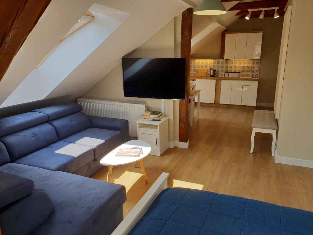 sala de estar con sofá azul y TV en Apartamenty Deptak en Ciechocinek
