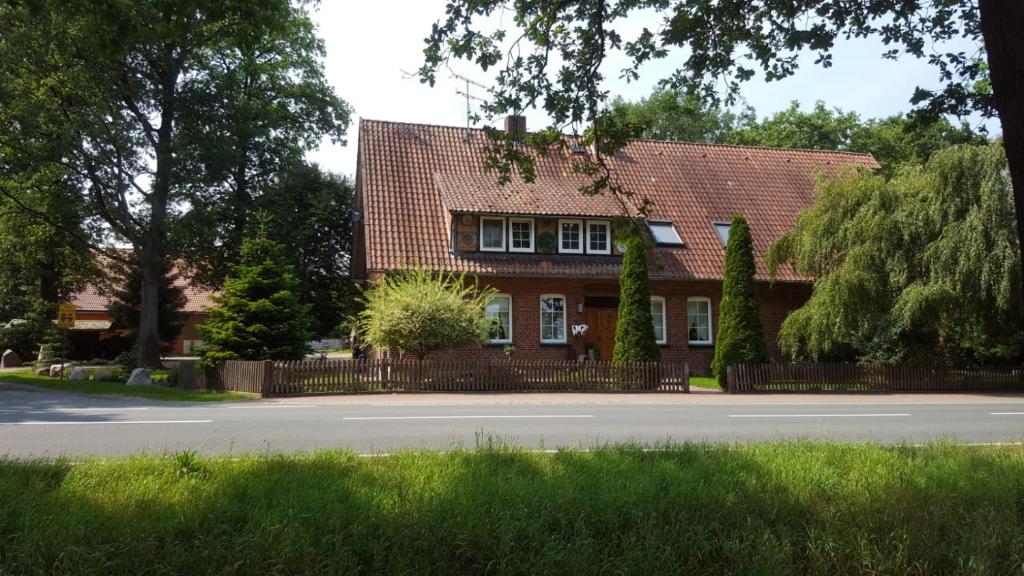 a red brick house with a fence in front of a street at Röhrshof in Bispingen