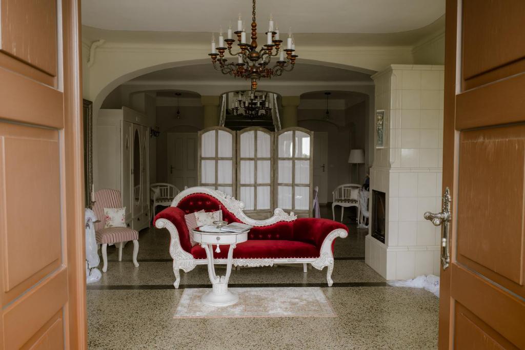 uma sala de estar com um sofá vermelho e uma mesa em HERRENHAUS KUNZWERDA bei TORGAU - ApartHotel, BoardingHouse, WOHNEN auf ZEIT em Torgau