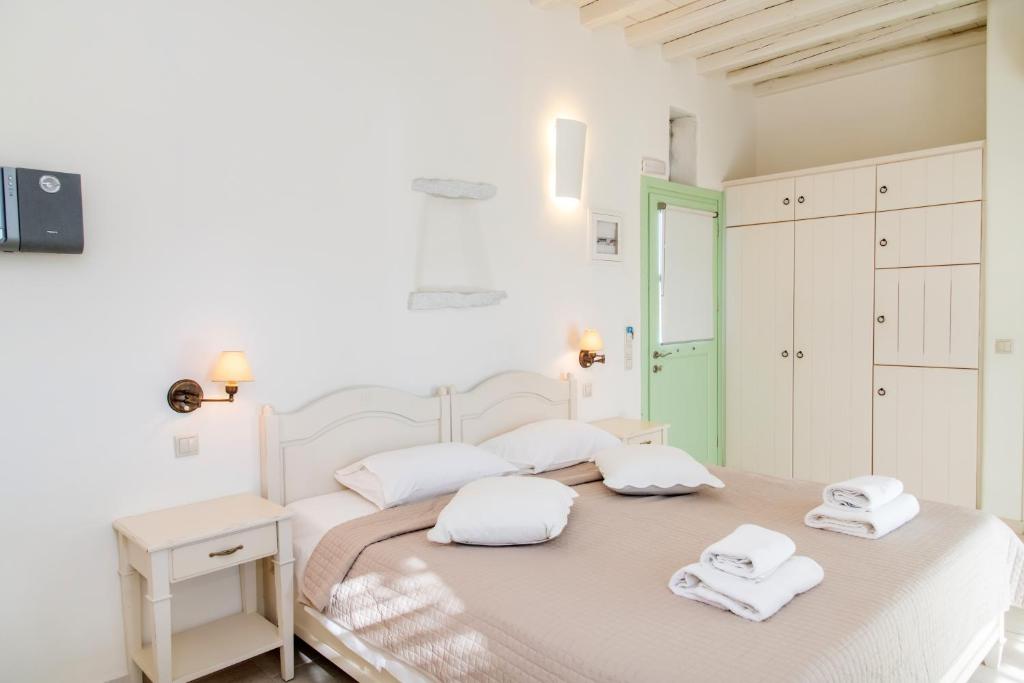 a white bedroom with a bed with towels on it at Anthea Hotel in Tinos Town