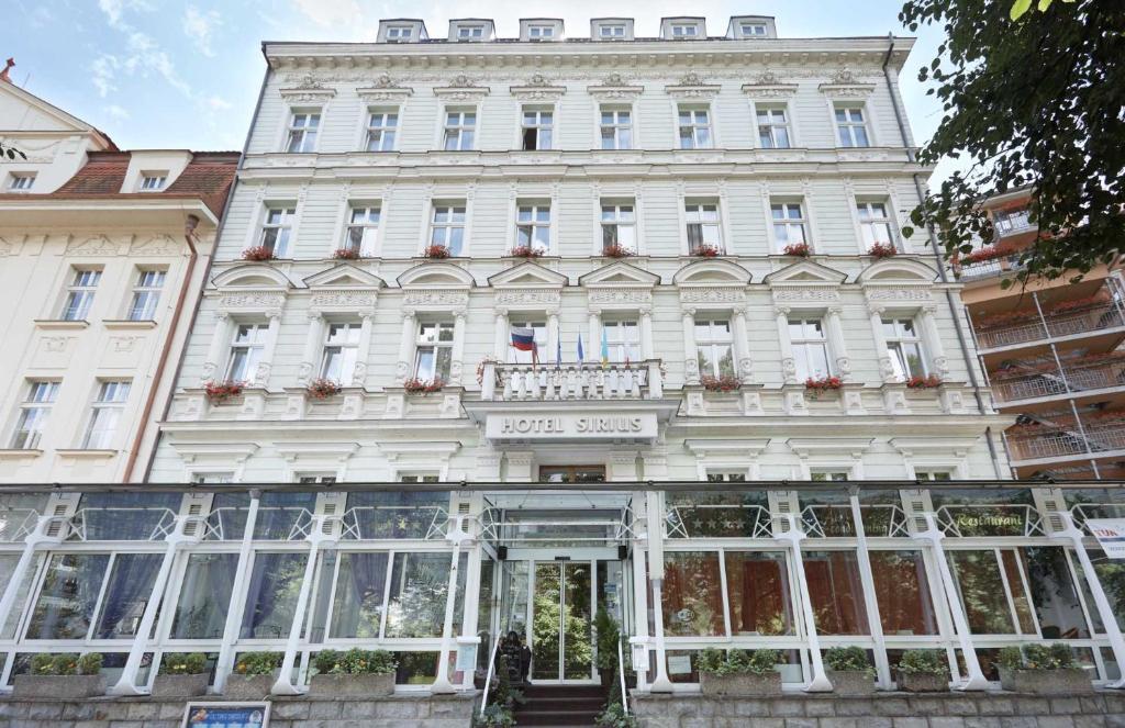 - un grand bâtiment blanc avec un panneau devant dans l'établissement Hotel Sirius, à Karlovy Vary