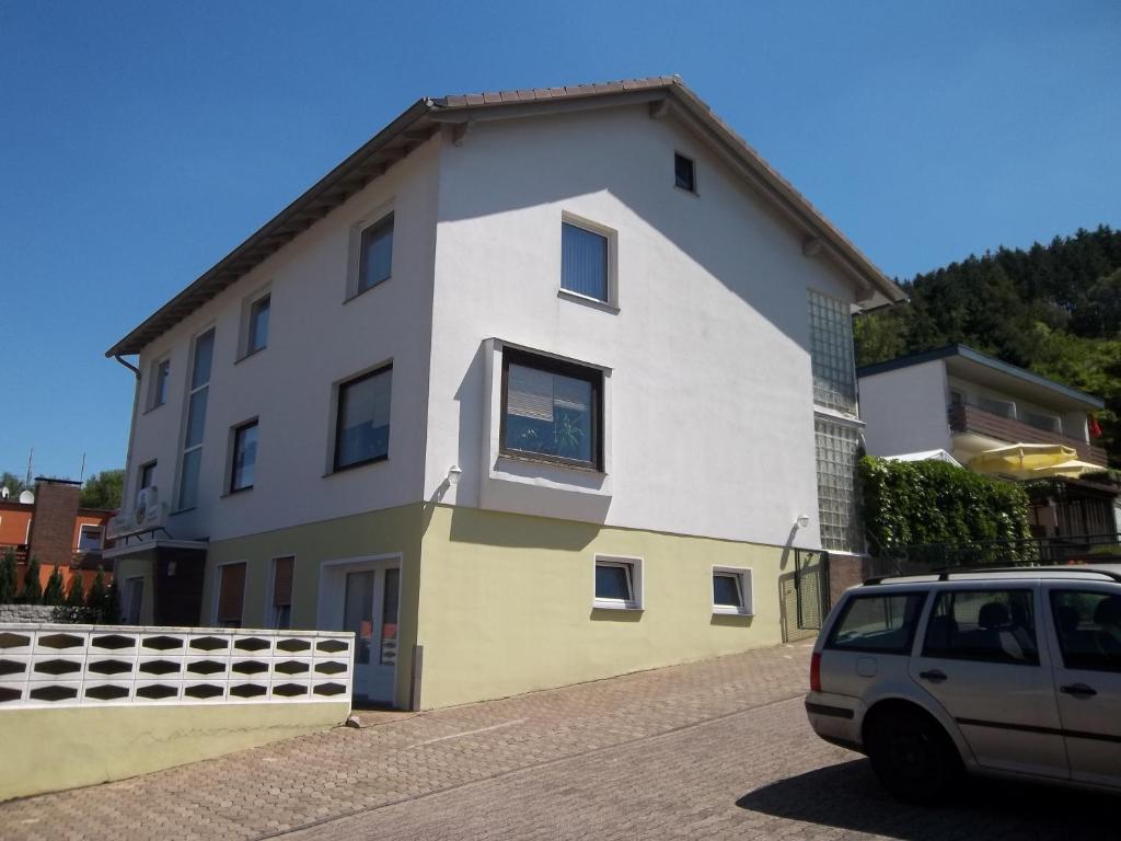 a white and yellow house with a car parked in front at Aktiv-Pension in Bad Karlshafen