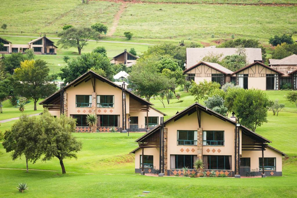 ein großes Haus auf einem grünen Feld mit Bäumen in der Unterkunft aha Alpine Heath Resort in Bonjaneni