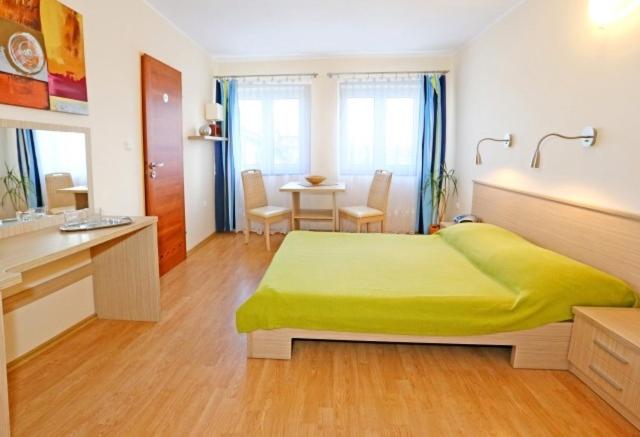 ein Schlafzimmer mit einem grünen Bett und einem Tisch in der Unterkunft Willa Patryk in Jastrzębia Góra