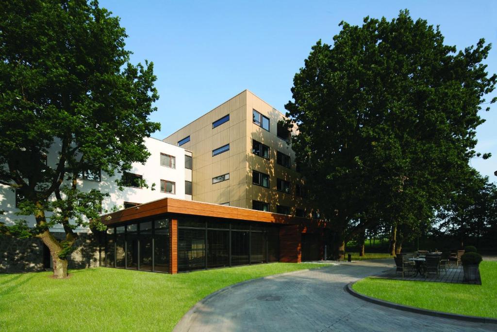 un edificio en un parque con césped y árboles en Fletcher Wellness-Hotel Stadspark en Bergen op Zoom