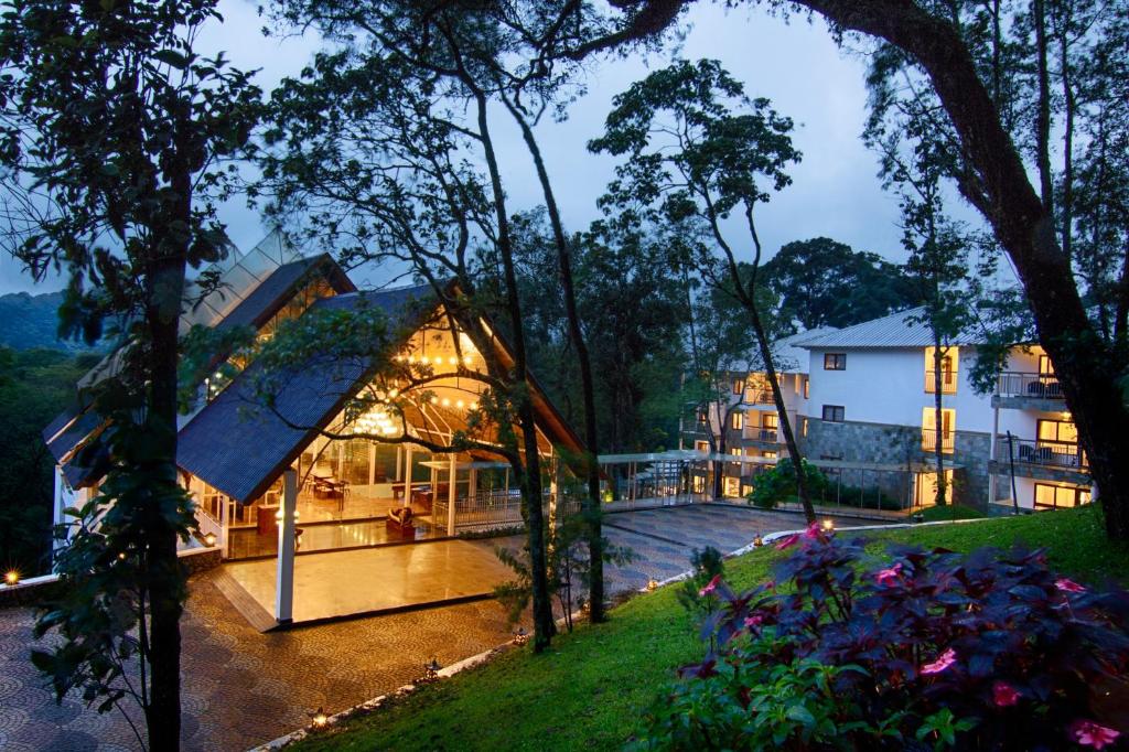 ein Haus inmitten eines Gartens mit Bäumen in der Unterkunft Elixir Hills Suites Resort and Spa in Munnar