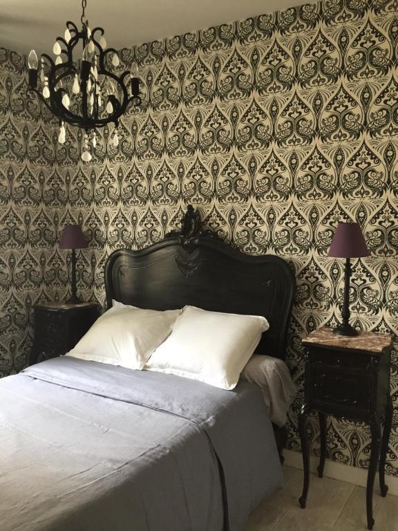 - une chambre avec un lit et un mur recouvert de papier peint dans l'établissement Au Carroir de France, à Saint-Aignan