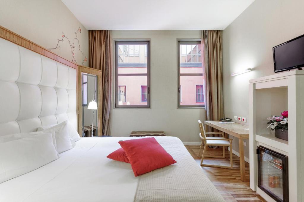 a hotel room with a large white bed with a red pillow at Italiana Hotels Milan Rho Fair in Rho