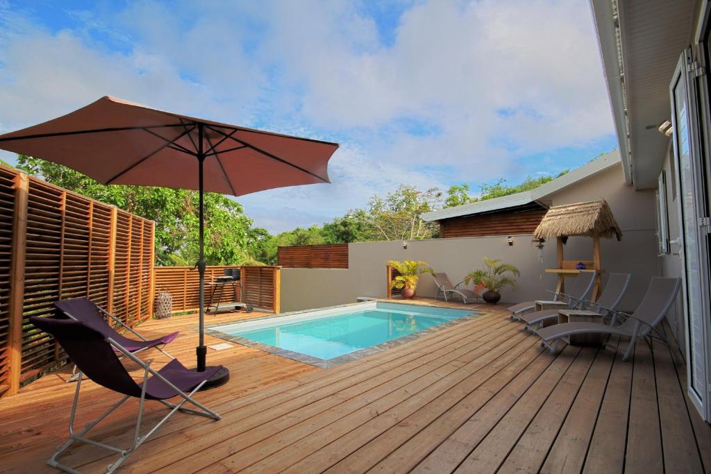 une terrasse avec un parasol, des chaises et une piscine dans l'établissement Villa with private pool MQDI53, au Diamant