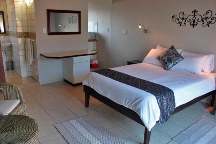 a bedroom with a bed and a desk in it at Lagoon Chalets in Walvis Bay