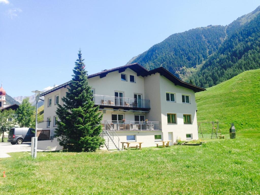 ein Gebäude mit einem Baum vor einem Hügel in der Unterkunft Apart Tyrol in Umhausen