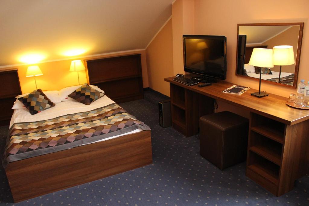 a hotel room with a bed and a desk with a television at Hotel Colnus in Kolno
