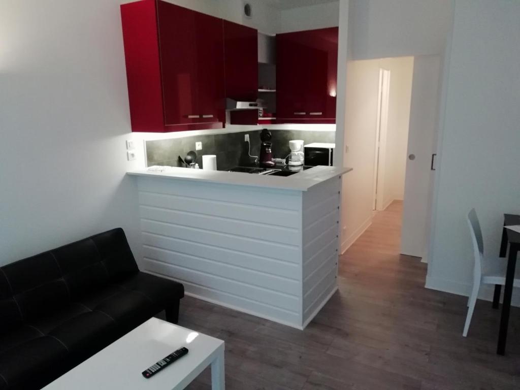 sala de estar con sofá y cocina con armarios rojos. en appartement de la place, en Dieppe