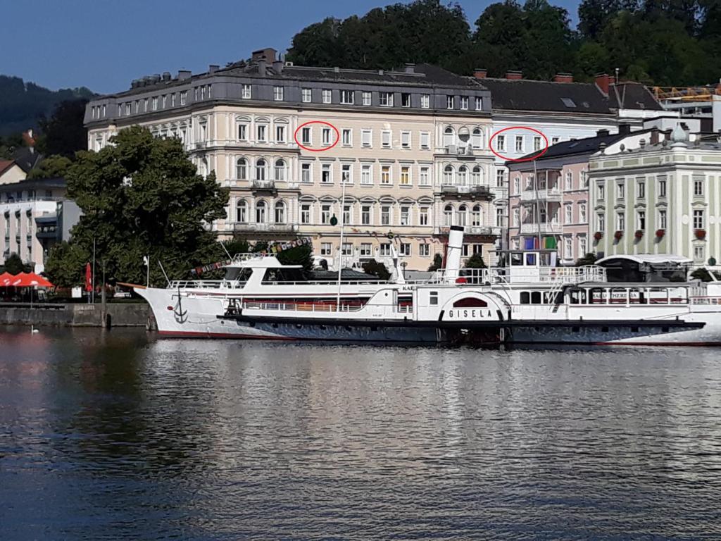 a large white boat in the water in front of buildings at Seeblick Apartment/Zimmer in Gmunden