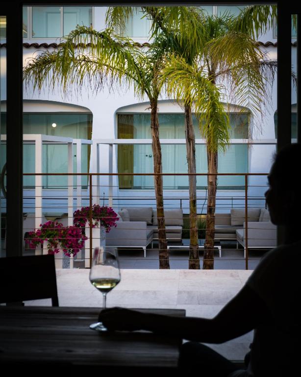 a person sitting at a table with a glass of wine at Hotel San Teodoro in San Teodoro